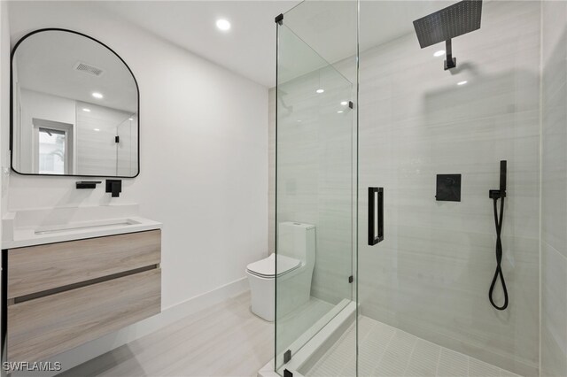 bathroom featuring vanity, a shower with shower door, and toilet