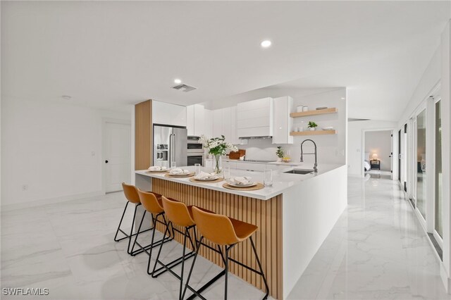 kitchen with white cabinetry, sink, a breakfast bar area, kitchen peninsula, and high end fridge