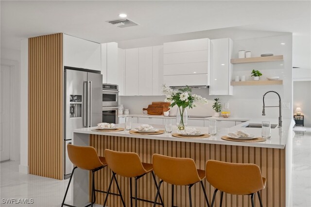 kitchen featuring appliances with stainless steel finishes, sink, a breakfast bar area, white cabinets, and kitchen peninsula