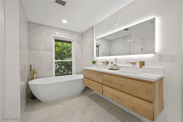 bathroom with vanity, a bathtub, and tile walls