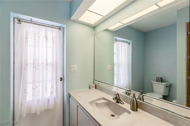 bathroom with toilet, a wealth of natural light, and vanity