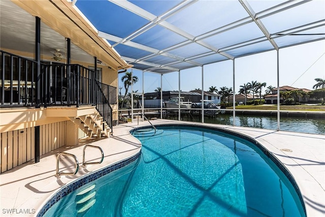 view of pool featuring a lanai, ceiling fan, a patio area, and a water view