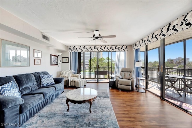 living room with ceiling fan, wood-type flooring, and a textured ceiling