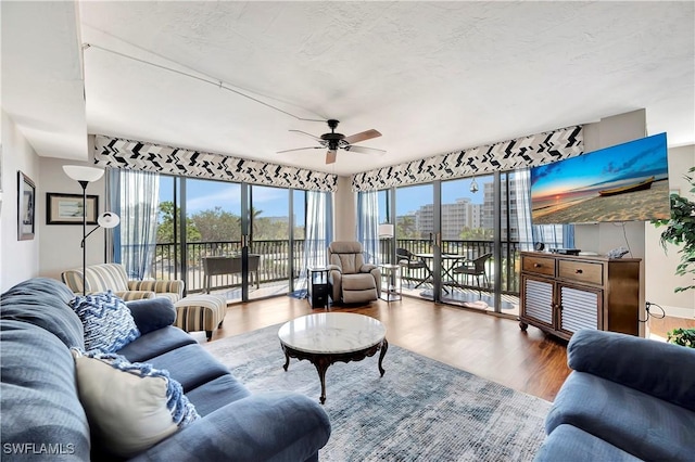 living room with wood-type flooring, a textured ceiling, a wealth of natural light, and ceiling fan