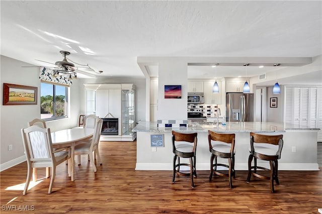 kitchen featuring pendant lighting, white cabinets, ceiling fan, a kitchen bar, and stainless steel appliances