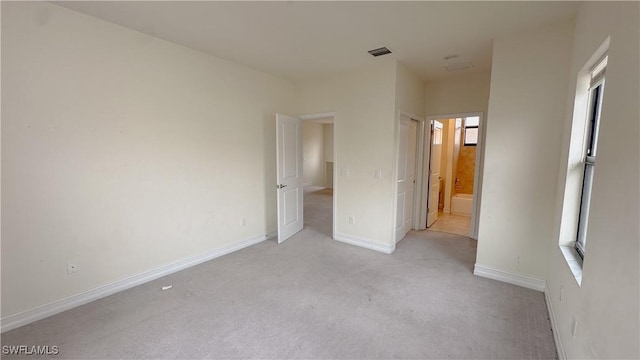 unfurnished bedroom featuring light colored carpet and ensuite bathroom