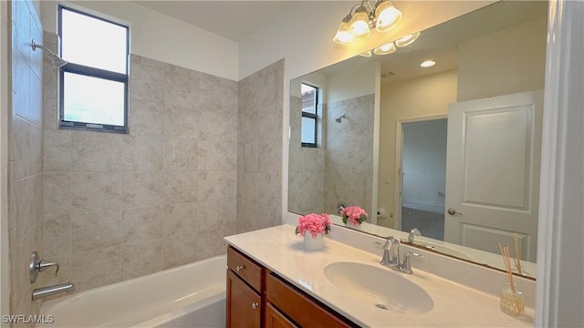 bathroom featuring tiled shower / bath, vanity, and a notable chandelier