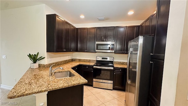 kitchen featuring kitchen peninsula, sink, light stone countertops, stainless steel appliances, and light tile patterned floors