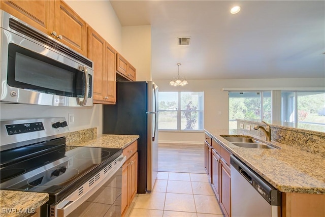 kitchen with sink, light stone counters, appliances with stainless steel finishes, and light tile patterned flooring