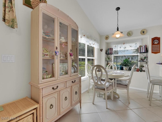 dining room featuring light tile patterned flooring, baseboards, and vaulted ceiling
