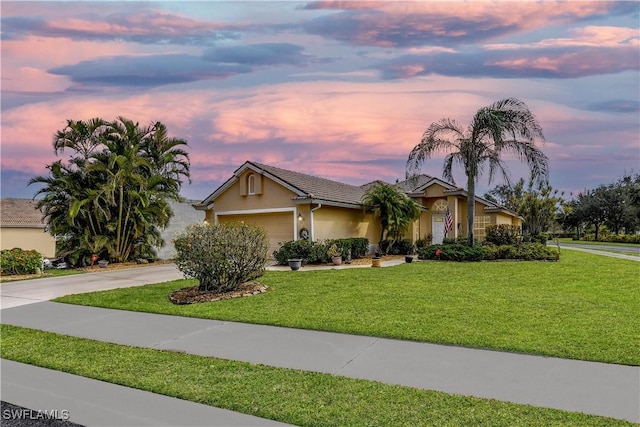 view of front of property with a tiled roof, a garage, concrete driveway, a front lawn, and stucco siding
