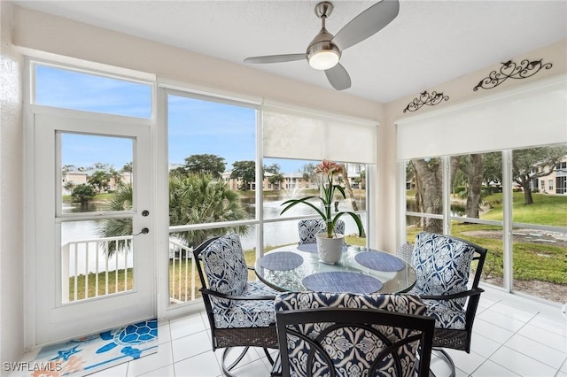 sunroom with ceiling fan and a water view