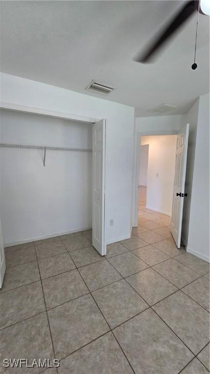 unfurnished bedroom featuring a closet, ceiling fan, and light tile patterned floors