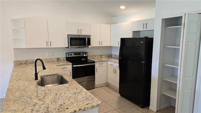 kitchen with appliances with stainless steel finishes, kitchen peninsula, light stone countertops, and sink