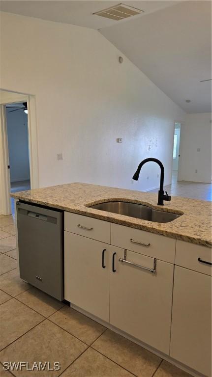 kitchen featuring vaulted ceiling, dishwasher, light tile patterned floors, white cabinets, and sink