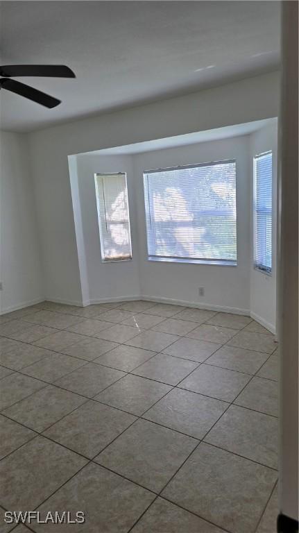 spare room with ceiling fan and light tile patterned floors