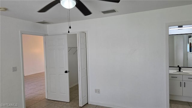 unfurnished bedroom with sink, connected bathroom, ceiling fan, and a spacious closet