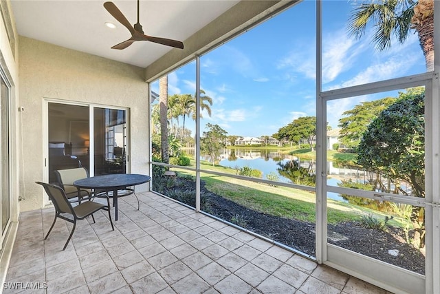 sunroom / solarium featuring ceiling fan and a water view