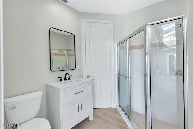 bathroom featuring toilet, an enclosed shower, wood-type flooring, and vanity