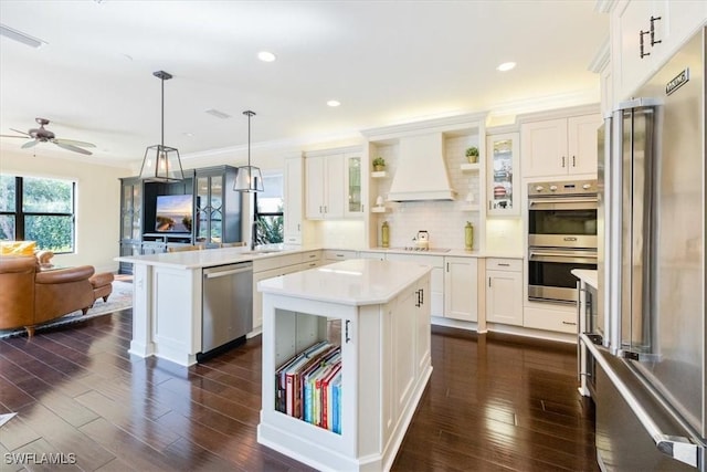 kitchen with a kitchen island, kitchen peninsula, appliances with stainless steel finishes, and custom range hood