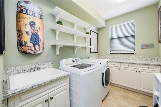 clothes washing area featuring sink, cabinets, washing machine and dryer, and light tile patterned floors