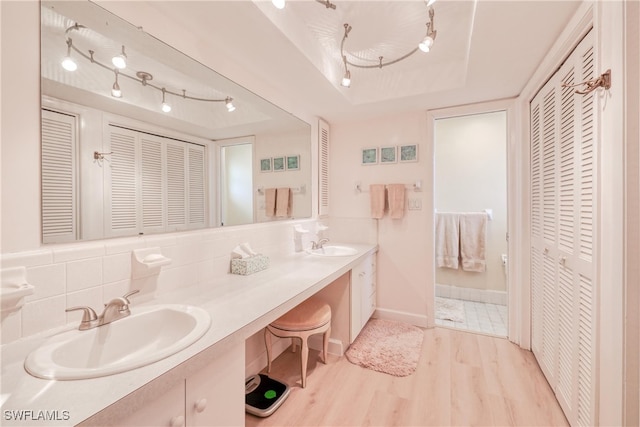 bathroom with hardwood / wood-style flooring, a tray ceiling, vanity, and tasteful backsplash