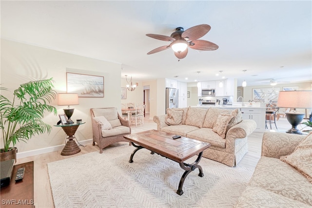 living room featuring sink, ceiling fan with notable chandelier, and light hardwood / wood-style floors