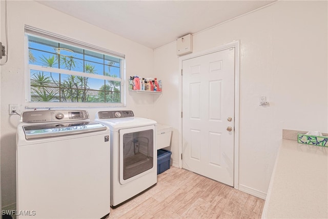 clothes washing area featuring washer and clothes dryer and light hardwood / wood-style flooring