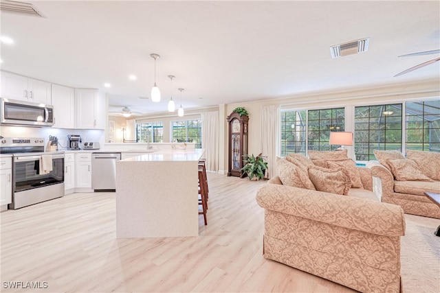 kitchen featuring a breakfast bar area, white cabinetry, stainless steel appliances, and pendant lighting