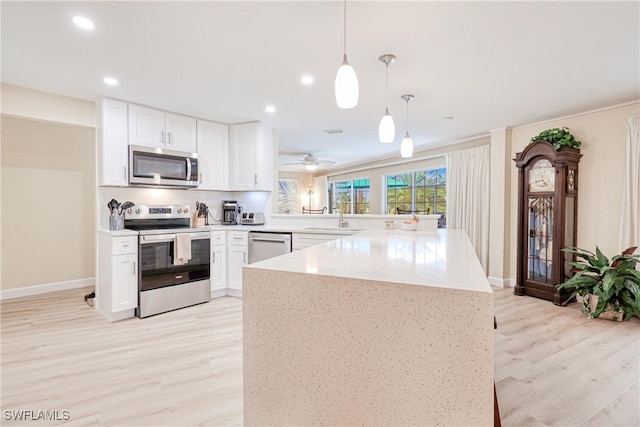 kitchen featuring white cabinetry, kitchen peninsula, appliances with stainless steel finishes, pendant lighting, and sink