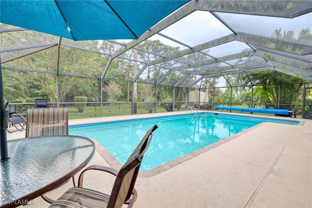 view of pool with glass enclosure and a patio area