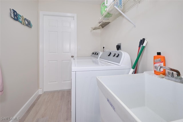 washroom with sink, separate washer and dryer, and light hardwood / wood-style flooring