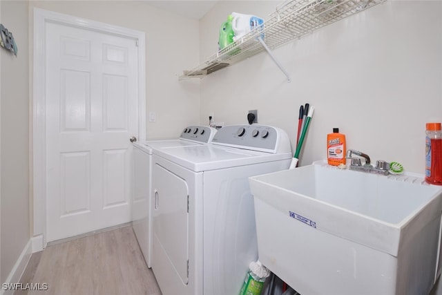 laundry room with washer and dryer, light hardwood / wood-style floors, and sink