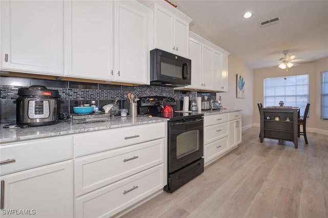 kitchen with light wood-type flooring, white cabinets, tasteful backsplash, and black appliances