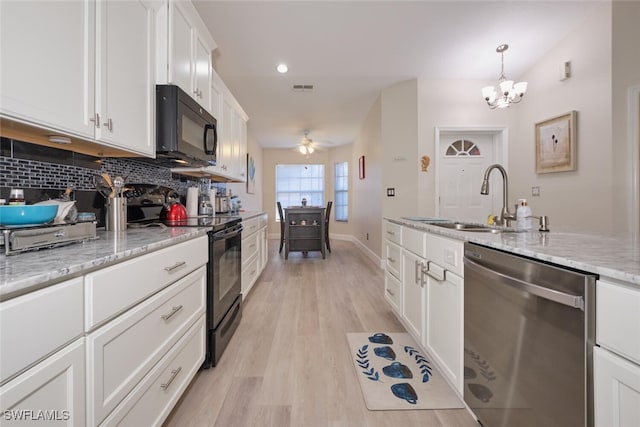 kitchen with decorative backsplash, light wood-type flooring, white cabinets, light stone counters, and black appliances