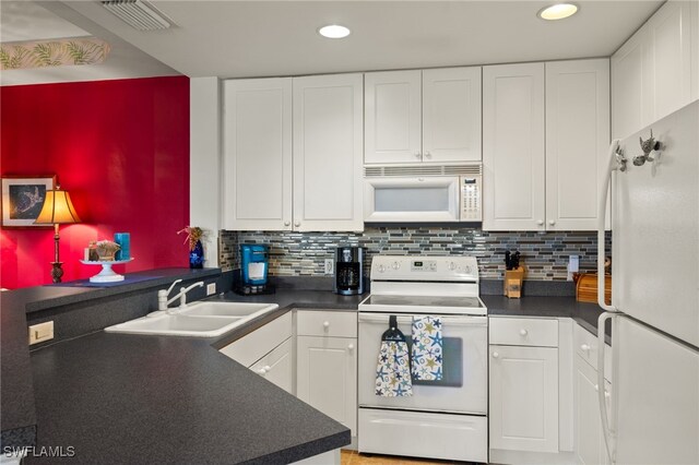 kitchen featuring white appliances, visible vents, white cabinets, dark countertops, and a sink