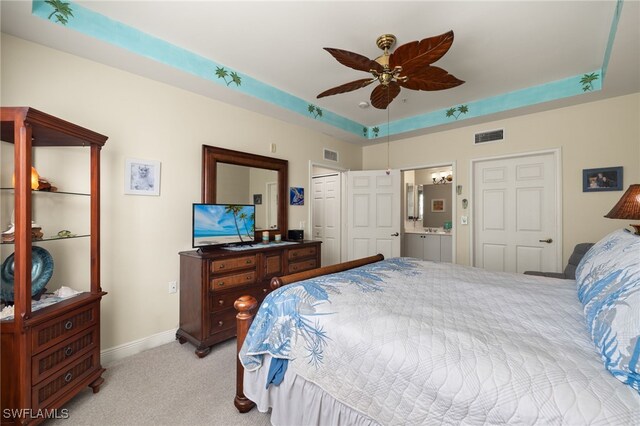 bedroom with light carpet, visible vents, a tray ceiling, and baseboards