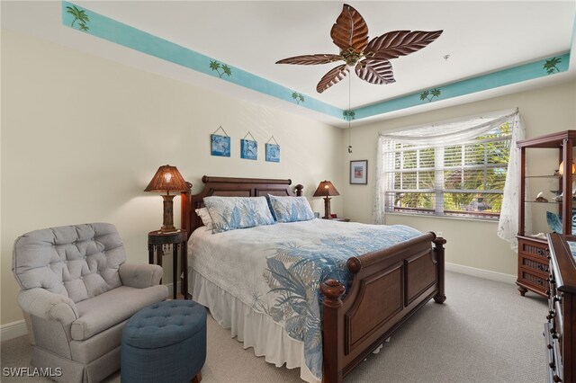 bedroom with ceiling fan, baseboards, a raised ceiling, and light colored carpet