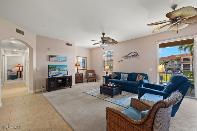 living room with light carpet, light tile patterned floors, visible vents, and arched walkways