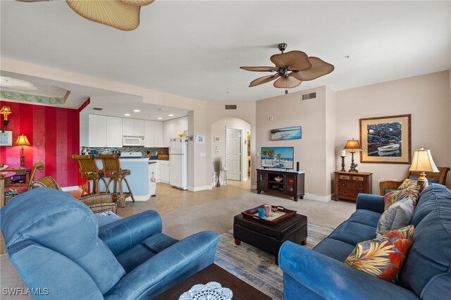 living area with arched walkways, a ceiling fan, visible vents, and baseboards