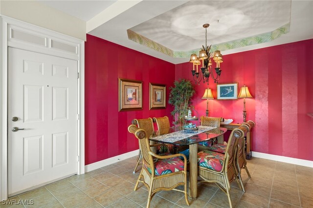 tiled dining area featuring baseboards, a chandelier, and a raised ceiling