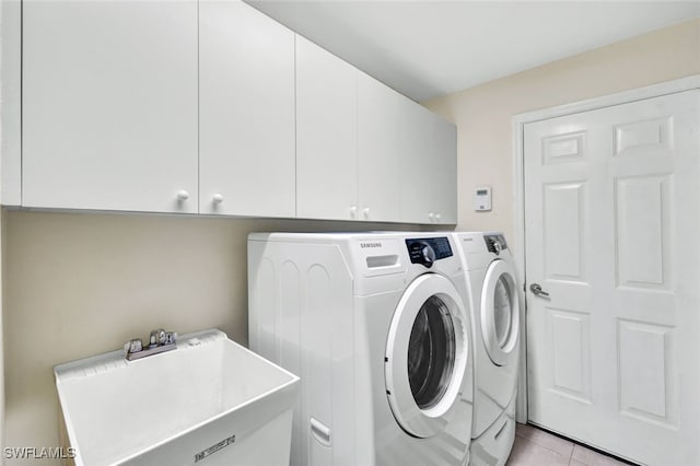 laundry room featuring washing machine and dryer, cabinets, light tile patterned floors, and sink