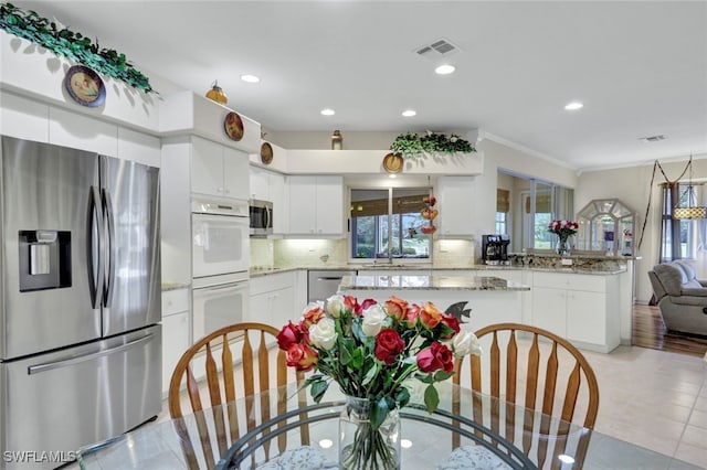 kitchen with tasteful backsplash, white cabinets, stainless steel appliances, and ornamental molding