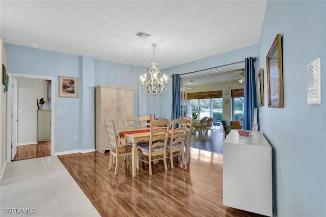 tiled dining space with ceiling fan with notable chandelier