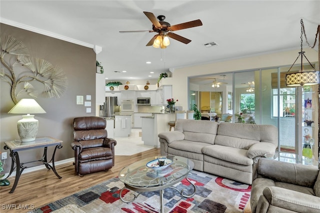 living room with light wood-type flooring, ceiling fan, and crown molding