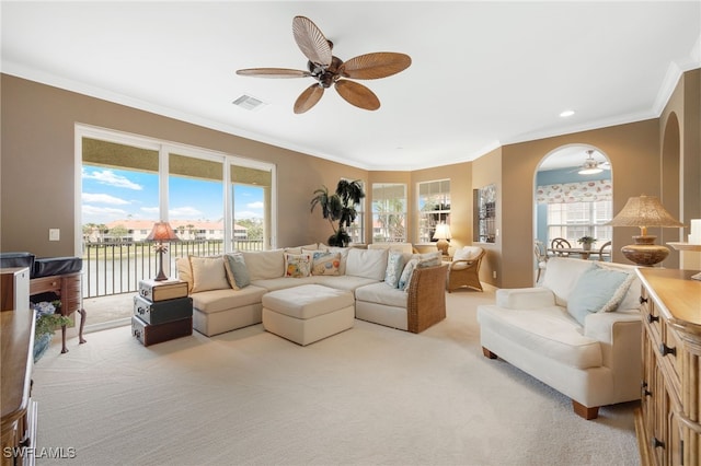 living area featuring crown molding, a ceiling fan, visible vents, and light colored carpet