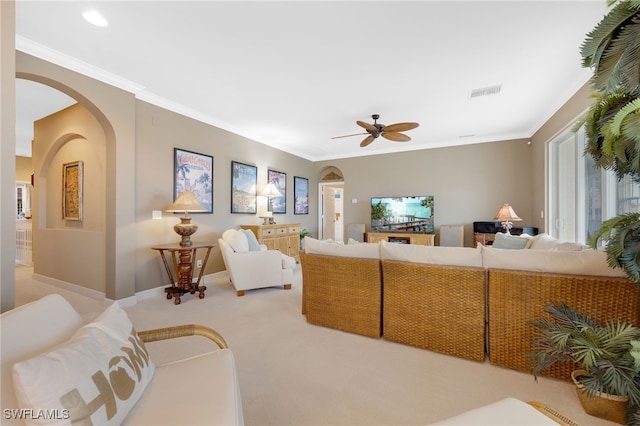 living area with arched walkways, visible vents, ornamental molding, light carpet, and baseboards