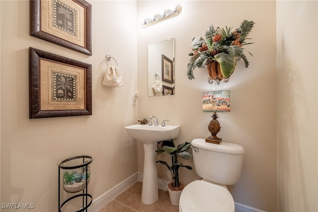 bathroom with toilet, baseboards, and tile patterned floors