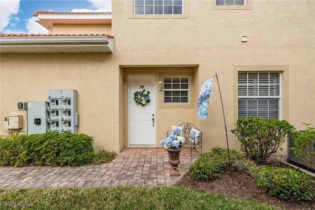 view of exterior entry with a tile roof and stucco siding