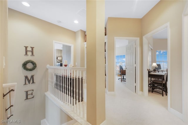 hallway featuring light carpet, recessed lighting, baseboards, and an upstairs landing